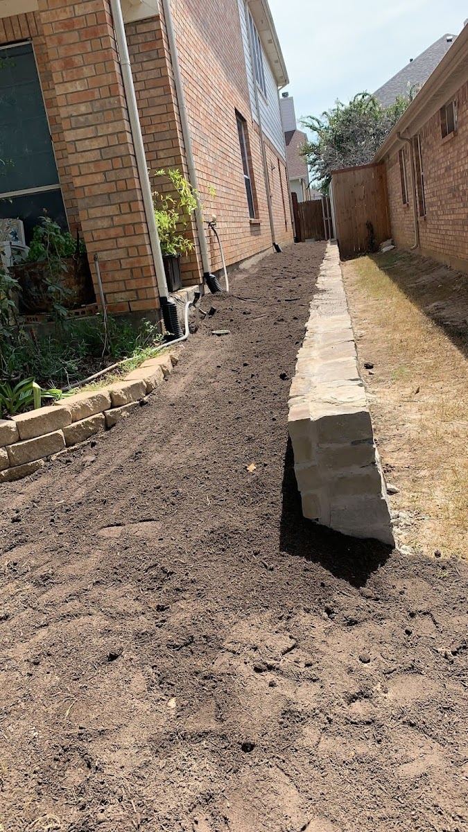 Regraded Texas side yard with fresh soil and a new stone retaining border
