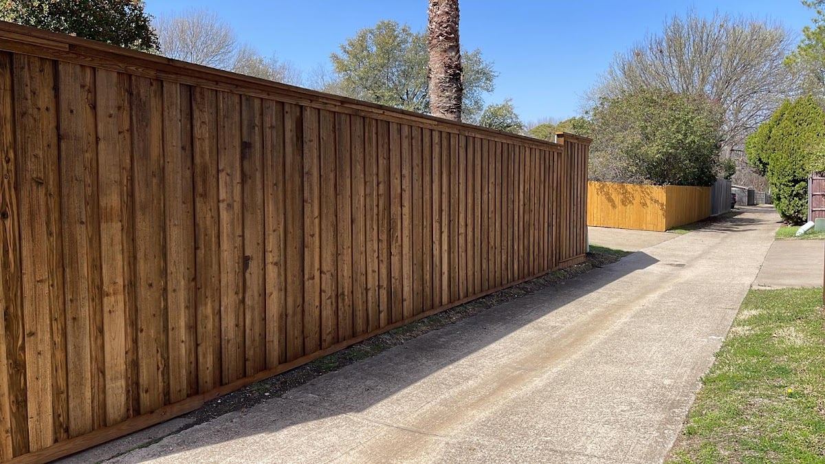 Newly built cedar privacy fence lining a driveway under sunny Fort Worth skies